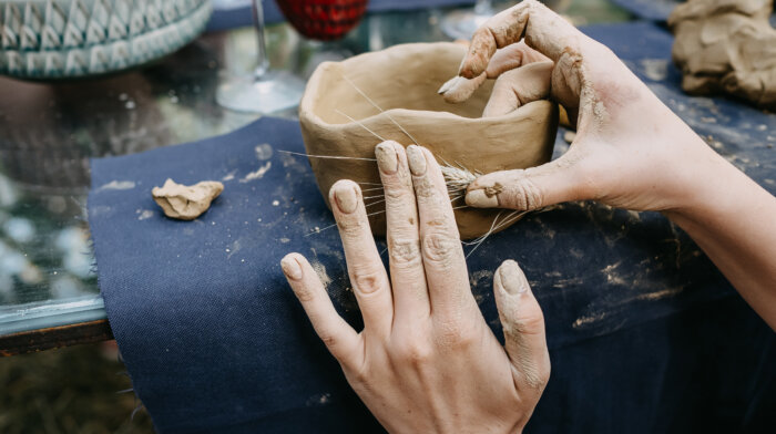 Close Up Of Human Hands Making A Clay Bowl. Pottery Teaching Class.